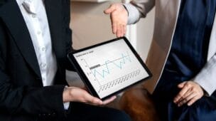 gestores analisando o track record de uma empresa através de um tablet