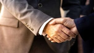 dois gestores apertando as mãos após acordo de fusão de empresas
