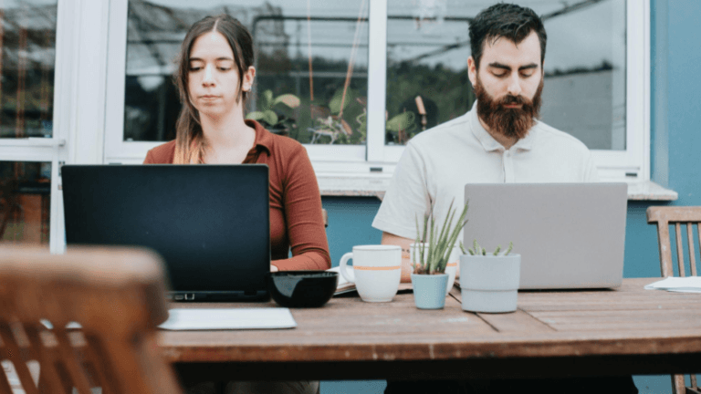 Esta imagem retrata um cenário de trabalho remoto ou co-working em um ambiente informal e tranquilo, possivelmente uma varanda ou área externa residencial.