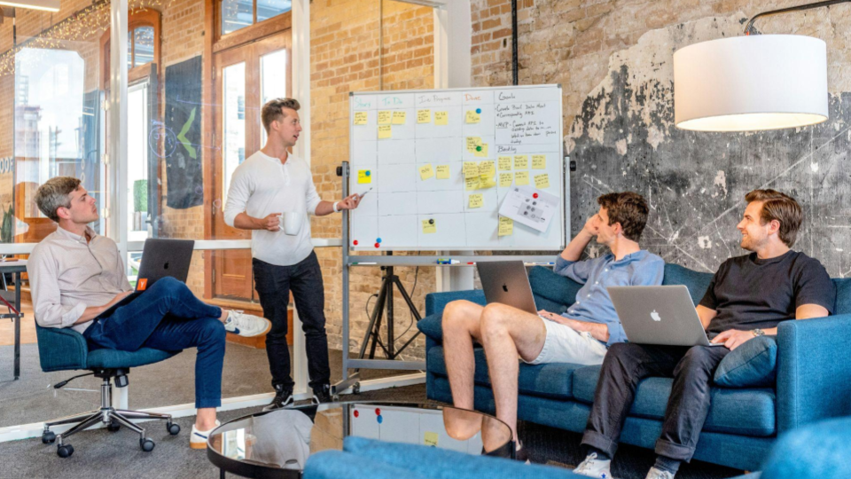 Esta imagem mostra um ambiente de startup ou agência criativa, com um clima muito mais descontraído e dinâmico.