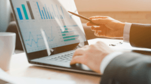 Executivo de terno utilizando um tablet durante uma reunião de negócios, representando análise estratégica, tomada de decisão e gestão empresarial baseada em dados.